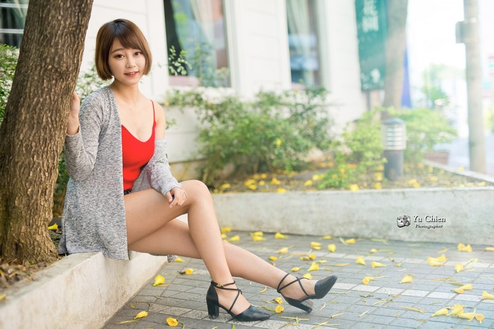 Asian woman with brown hair sitting outdoors