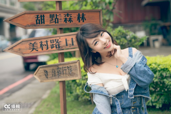 Brunette girl in denim overalls near signpost