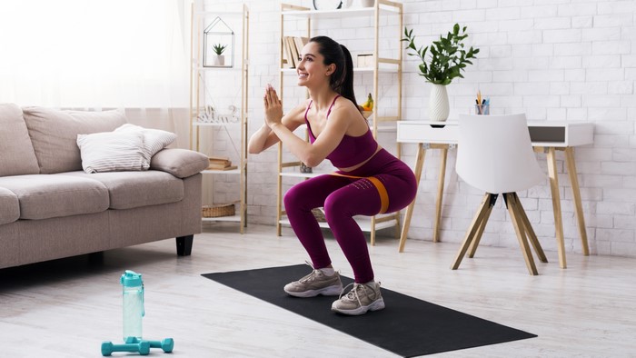 Woman doing squats with resistance band