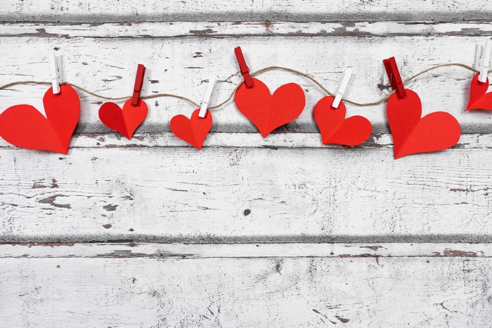 Red paper hearts on a clothesline against wood planks