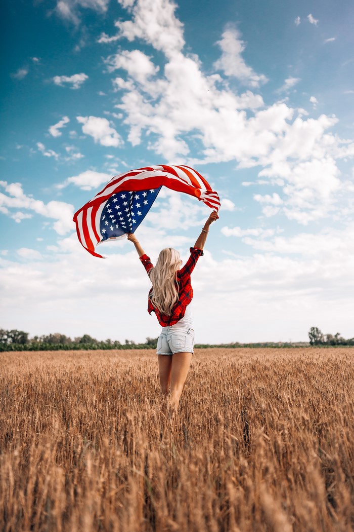 Woman holding American flag in a field