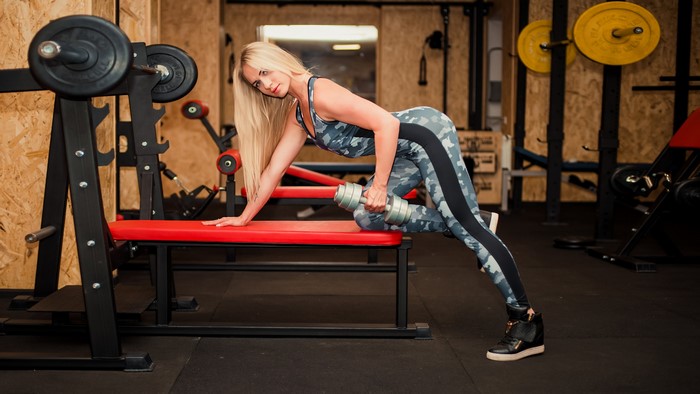 Blonde woman doing dumbbell workout in gym