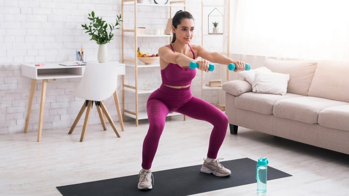 Woman doing squats with dumbbells