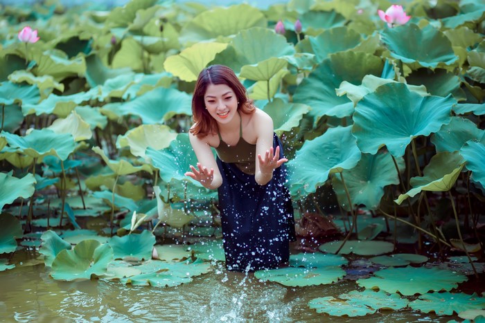 Woman splashing water in a lotus pond