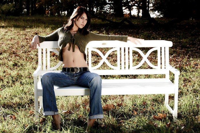 Brunette girl sitting on a bench in grass