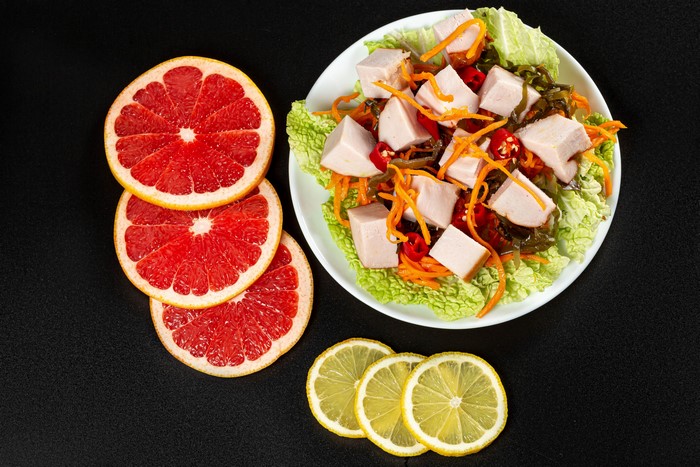 Salad with grapefruit and lemon slices on a black background