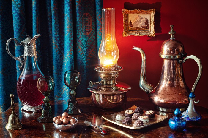 Still-life with kerosene lamp, wine, and chocolates