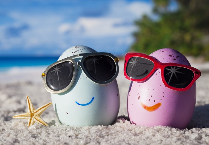 Two decorated eggs with sunglasses on a beach