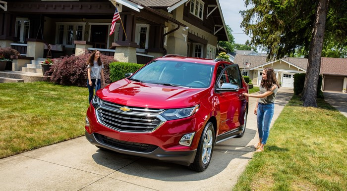 Red Chevrolet Equinox Premier Crossover in front of a house