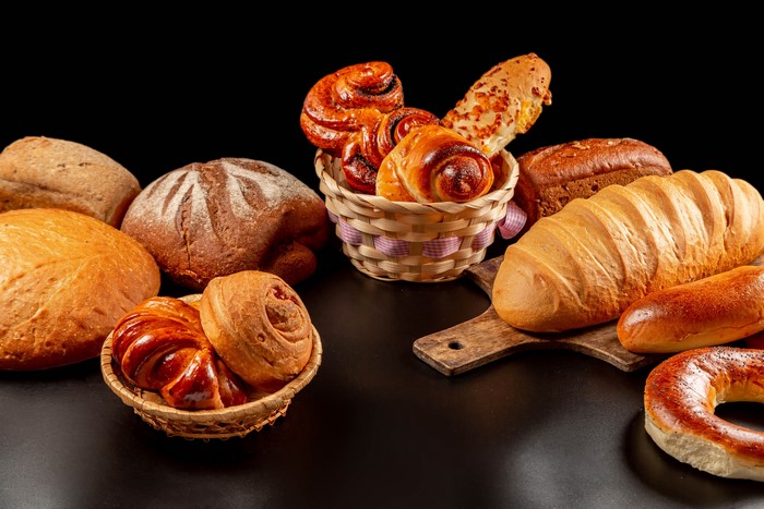 Assortment of Breads and Pastries in Wicker Baskets and on Cutting Board