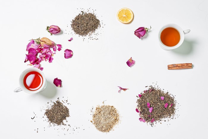 Tea, Cinnamon, Lemon, and Rose Petals on White Background