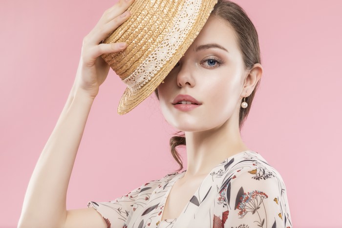 Woman with straw hat on pink background