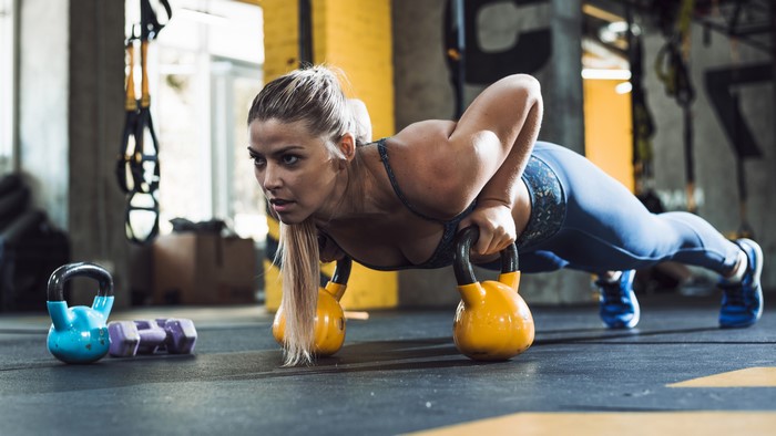 Woman doing kettlebell push-ups in a gym