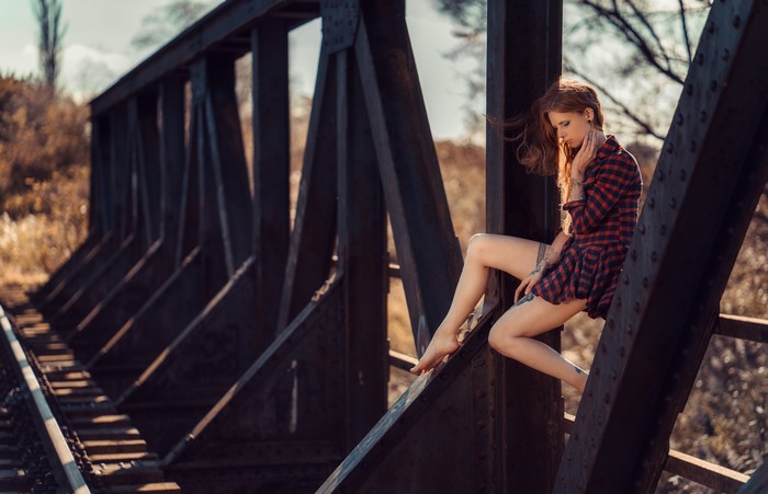Woman with red hair sitting on a bridge