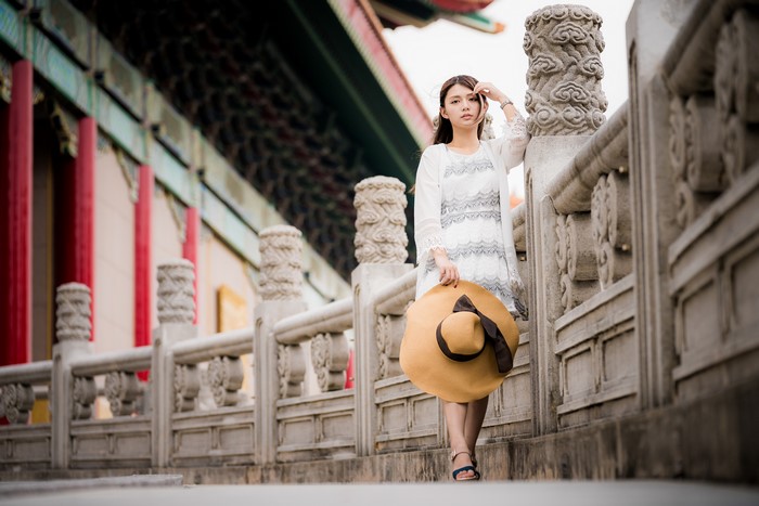 Asian woman with hat in front of traditional building