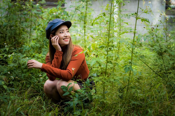 Asian woman wearing a baseball cap and sweater in grass