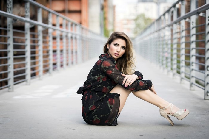 Woman in floral dress sitting on a bridge