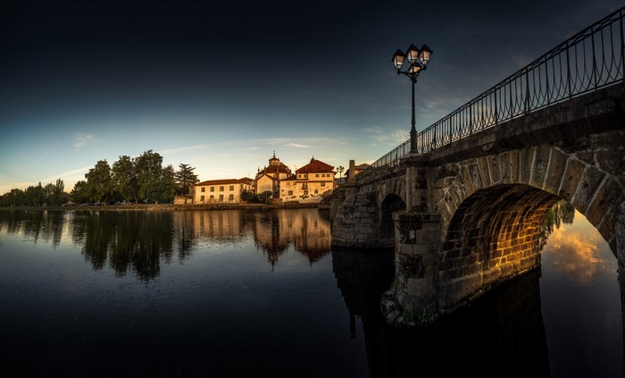 Stone bridge over river with buildings and street light in Portugal