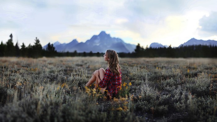 Woman in field with mountains in background