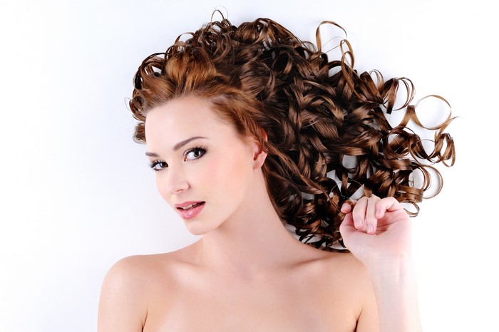 Brown haired woman with curly hairstyle on white background
