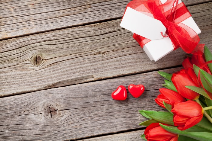 Valentine's Day gift box with red tulips and hearts on wood