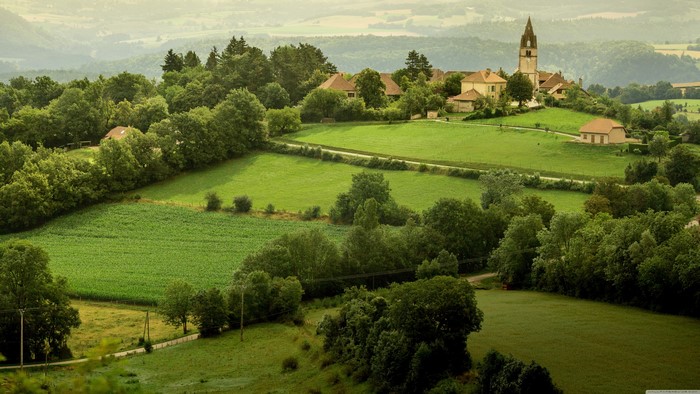 Village with church in green fields, France