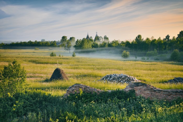 Morning fog over a Russian grassland with church