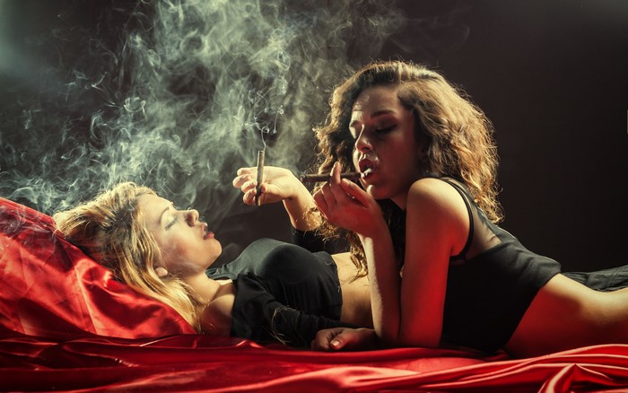 Two women smoking cigars in smoke