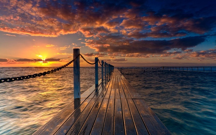 Wooden pier extending into the ocean at sunset
