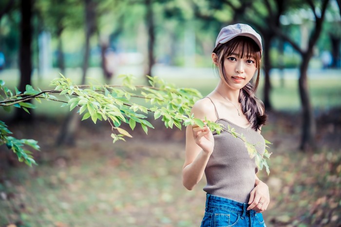 Asian girl in baseball cap and singlet in park