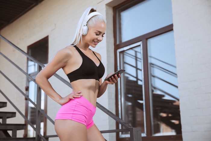 Blonde woman with headphones and smartphone on stairs