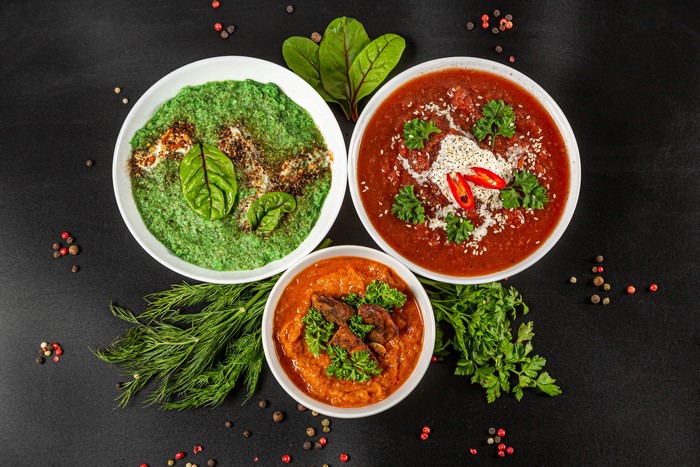 Three bowls of soup with dill and peppercorns