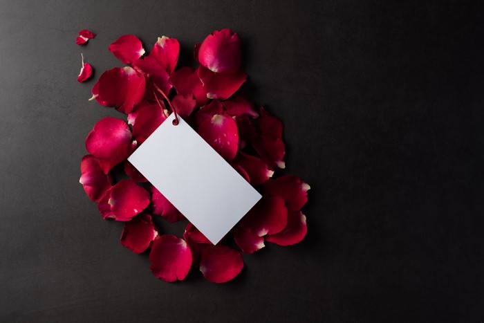 Red rose petals with a blank tag