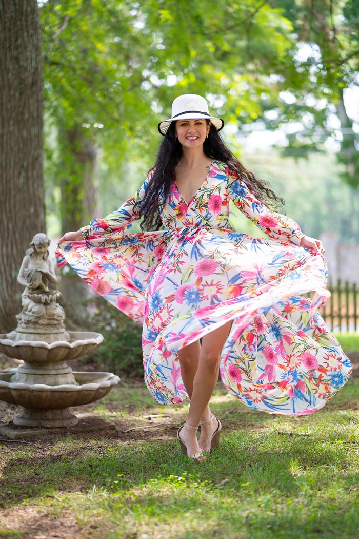 Woman in floral dress and hat spinning in garden