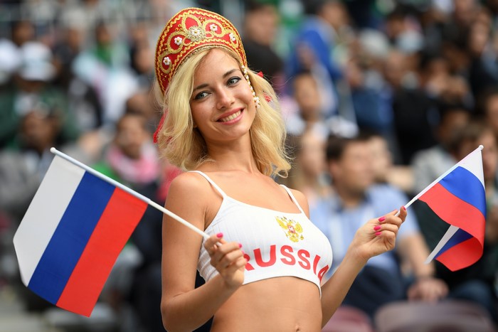 Blonde woman in Russian attire holding flags