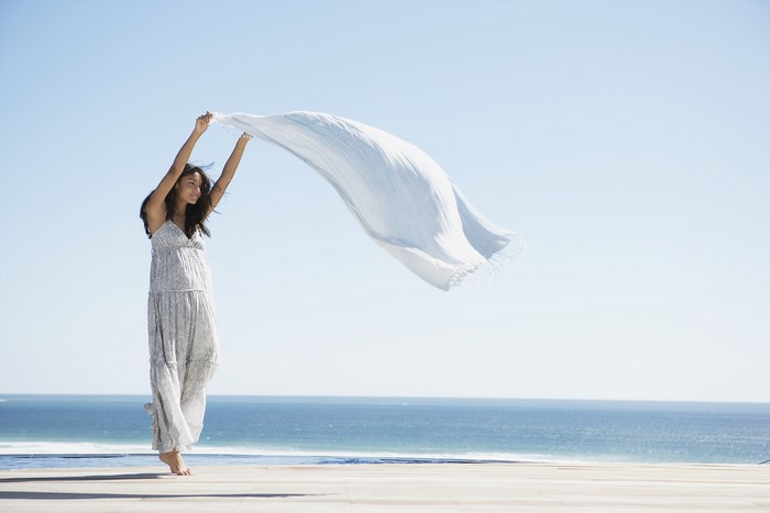 Brunette girl holding a towel by the sea