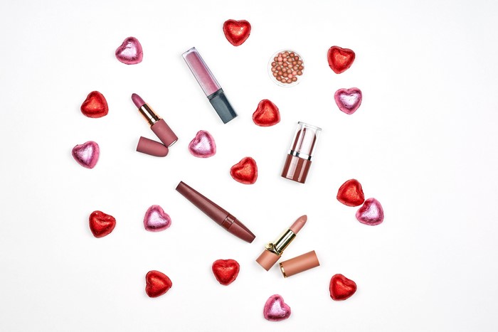 Lipsticks and heart candies on white background