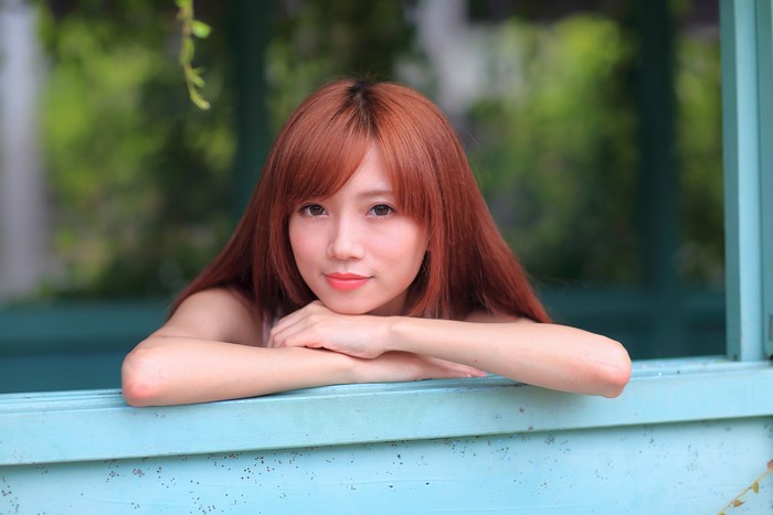 Asian woman with red hair resting chin on hands
