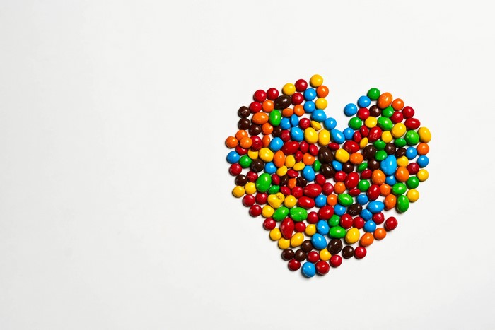 Heart shape made of colorful candies on a gray background