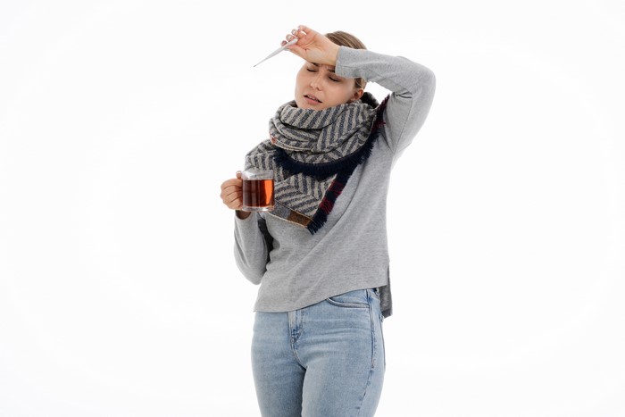 Woman with thermometer and tea, common cold