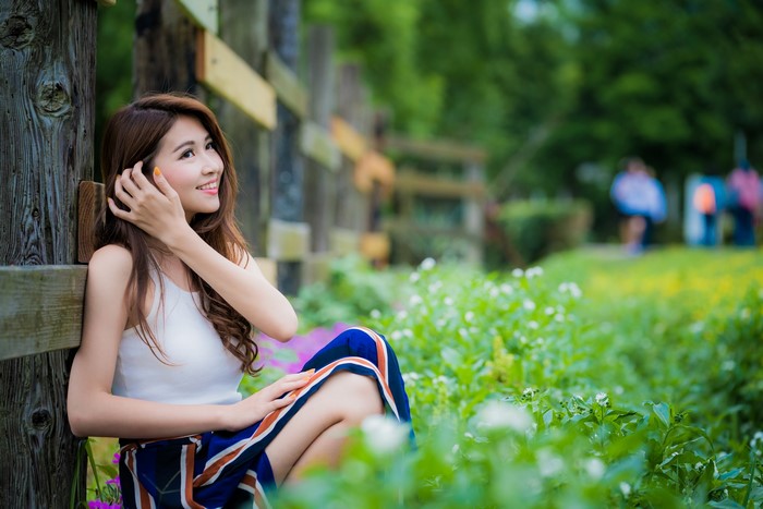 Asian woman with brown hair sitting in a grassy field