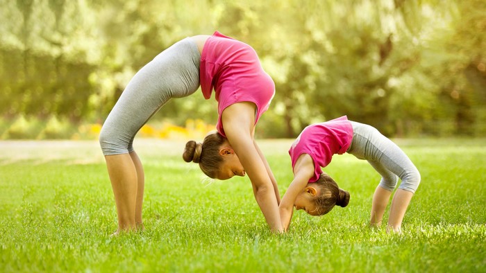 Two girls doing gymnastics on grass