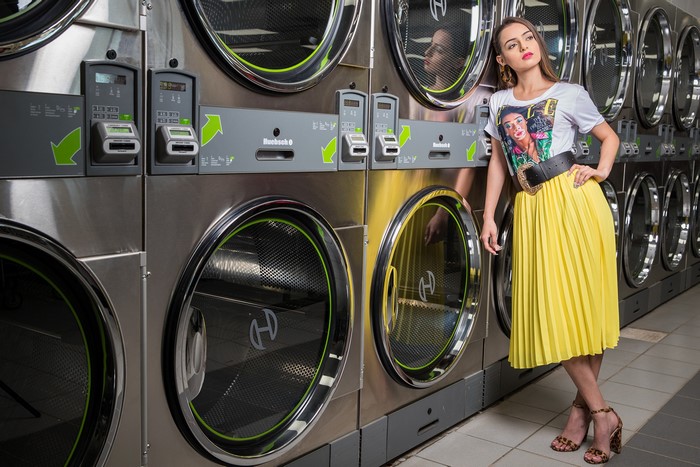 Alexis Contreras in a yellow skirt and t-shirt at a laundromat
