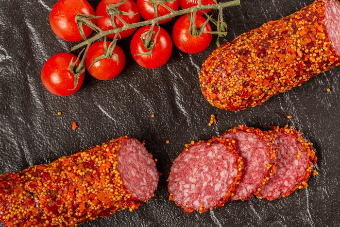 Sausage with tomatoes on a dark surface