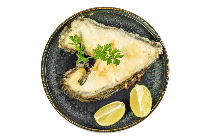 Fried fish fillet with lime and parsley on a plate