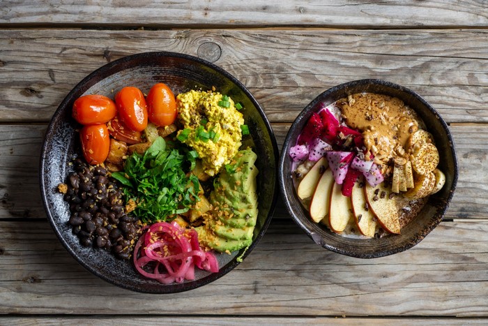 Two bowls of food with fruits and vegetables