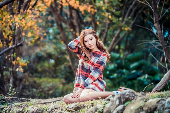 Asian woman in plaid dress sitting in park