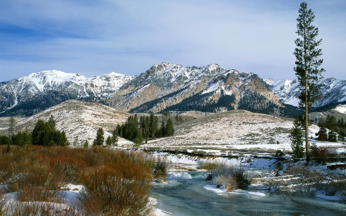 Snow-covered mountains and a partially frozen river in winter