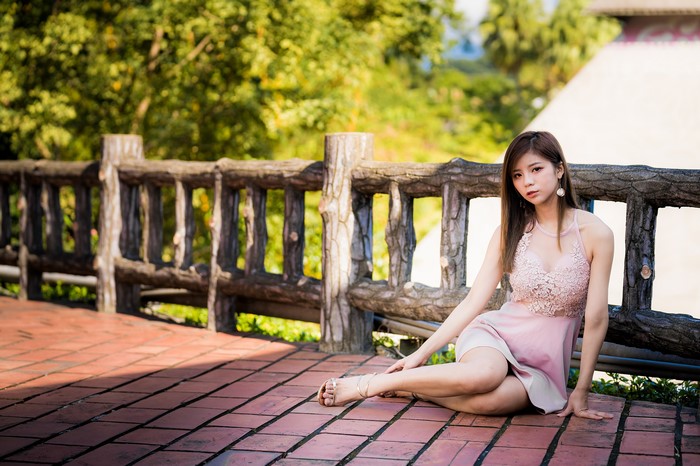 Asian woman with brown hair sitting by a fence