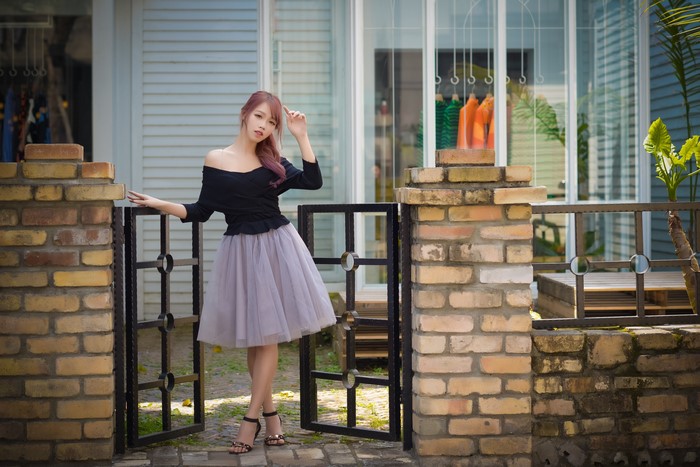 Asian woman in black off-shoulder top and grey skirt